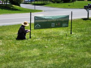 Staff member securing our Pollinator habitat in progress! sign. Staff member securing our Pollinator habitat in progress! sign.